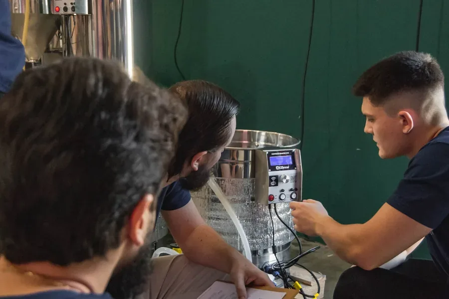 Equipe da EZbrew produzindo cerveja junto ao equipamento